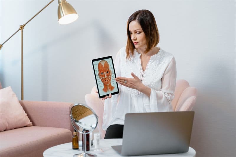 Specialistă arătând pe o tabletă o planșă anatomică a feței